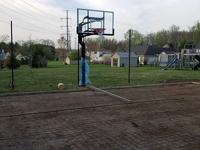 Already-installed hoop overlooking form and reinforcement for the concrete base for a dark green and grey backyard basketball court in Agawam, MA.