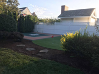 Backyard basketball court featuring Celtics logo and adjacent putting green by our partner in Barnstable, MA.