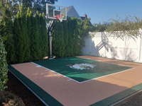 Backyard basketball court featuring Celtics logo and adjacent putting green by our partner in Barnstable, MA.