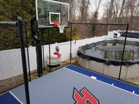 Former small, unused space in back yard by above ground pool became the home of a small blue and grey basketball court in Braintree, MA.