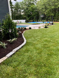 Distance view of blue and gray residential basketball court in Easton, MA, highlighting the partner work by Evergreen Landscaping.