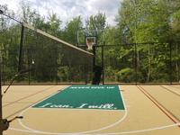 Large mixed use court in Londonderry, New Hampshire. Primary color is sand, with emerald gree secondary and custom text on the key, plus two custom logos in corners not shown here. Court is lined for secondary sports besides basketball, with an optional net so it can be used for tennis or volleyball particularly.