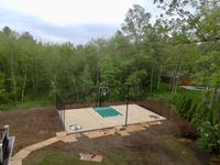 Tan and green basketball court in Londonderry, NH, featuring multiple custom logos and writing, lighting for night play, and optional multicourt net for volleyball.