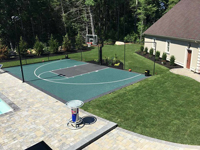 Green and black basketball court in Marion, MA, shown after completion of surrounding landscaping and pool.