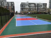 Angled view down the length of pickleball court with apartment buildings on D Street in background, at Lawn on the D in Boston, MA Seaport District, MA.