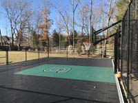 Backyard basketball court, black with green key and custom logo, with optional fencing in Canton, MA.