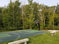 Basketball court in shades of green in park-like backyard in Dartmouth, MA.