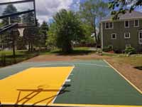 Backyard basketball court in olive green and yellow in Easton, MA.