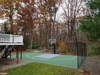 Olive green and grey basketball court with hoop and fencing in Hopkinton, MA.