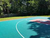 Emerald green and rust red home basketball court in Lynnfield, MA, featuring custom Celtics logo.
