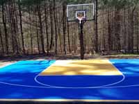 Home basketball court in Medway, MA, featuring royal blue and yellow Versacourt outdoor sport surface tiles.