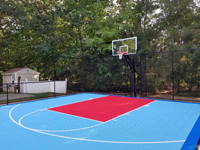 Tricolor backyard basketball court with fencing, surfaced in royal blue, light blue, and red, in North Attleboro, MA.