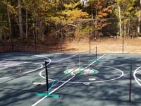 Mostly green, mostly basketball court in Raynham, MA, with portable net, lines and accessories shown for playing pickleball.