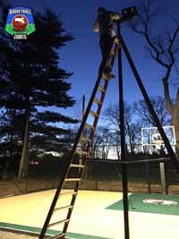 Bob adjusting optional lighting installed with outdoor basketball court in Swampscott, MA.