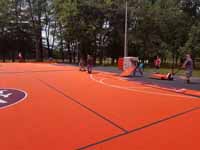Surfaced giant multiple basketball court at Frost Valley YMCA in Claryville, NY. Features orange, black and burgundy tiles, plus custom logos.