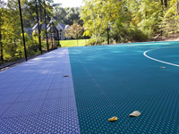 Relatively close view of Versacourt tile that makes up the surface of large emerald green and titanium backyard basketball court in Bolton, MA, looking down much of the length of one side, along the containment fence.